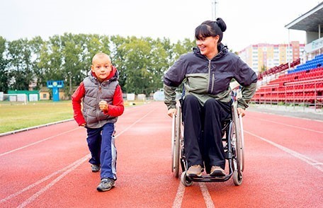 Boy and woman in a wheelchair on a track field 